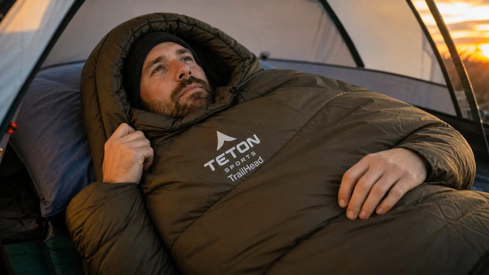 TETON TrailHead sleeping bag packed into its compression sack next to a loaded backpack on a trail